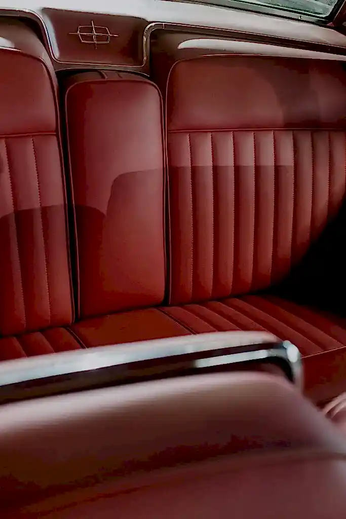 Classic car interior showcasing elegant red leather seating and retro design details.